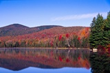 Fall color on hillside with lake reflection.