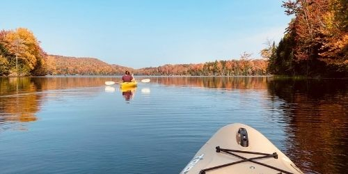 POV of visitors paddling along Green River Reservoir in kayaks amongst golden fall foliage